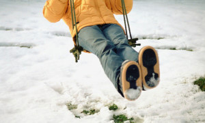 Child swinging on snowy playground