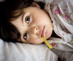 child with fever resting in bed